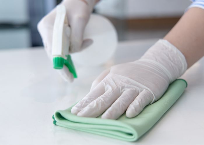 sanitizing a table wearing gloves to protect your hands from chemicals